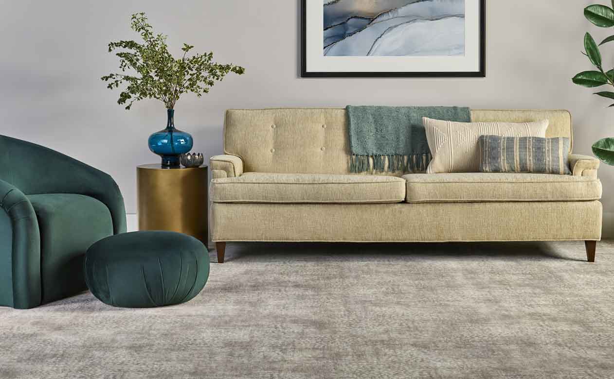 neutral plush carpet in living area with cream mid centruy modern sofa and green armchair